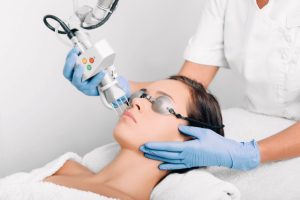 woman wearing protective glasses, getting laser facial treatment. Facial skin rejuvenation